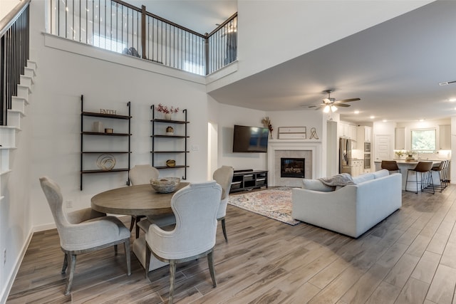 dining room featuring a tile fireplace, hardwood / wood-style flooring, and ceiling fan