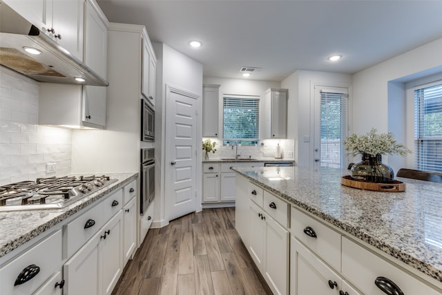 kitchen featuring light stone countertops, sink, light hardwood / wood-style floors, white cabinets, and appliances with stainless steel finishes