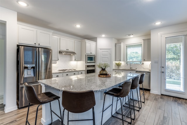 kitchen featuring a breakfast bar, a center island, light hardwood / wood-style flooring, white cabinetry, and stainless steel appliances