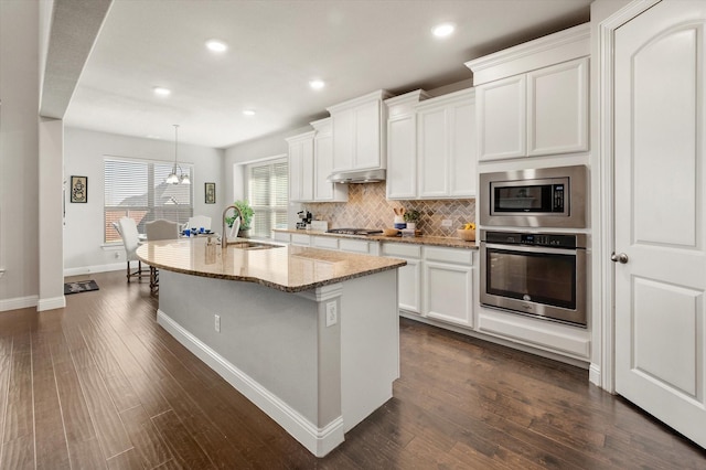 kitchen featuring appliances with stainless steel finishes, decorative light fixtures, white cabinetry, an island with sink, and sink