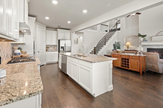 kitchen with appliances with stainless steel finishes, sink, white cabinets, an island with sink, and decorative backsplash