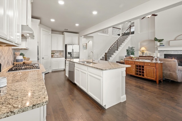 kitchen featuring sink, an island with sink, appliances with stainless steel finishes, dark hardwood / wood-style flooring, and white cabinetry