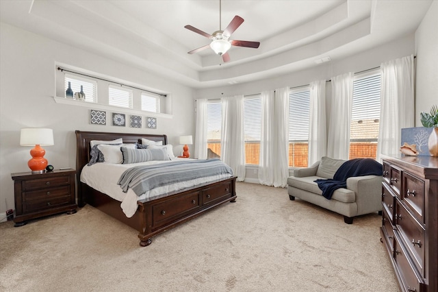 bedroom with ceiling fan, light carpet, and a raised ceiling