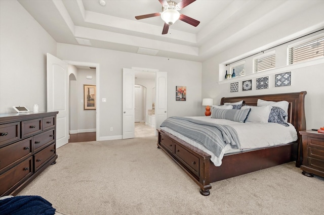 carpeted bedroom with ceiling fan and a raised ceiling