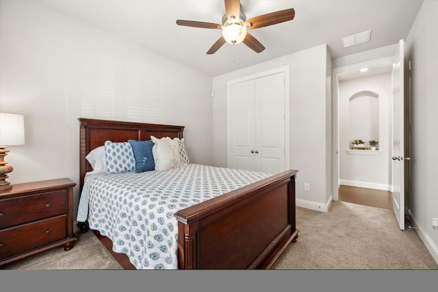 bedroom with ceiling fan, light colored carpet, and a closet