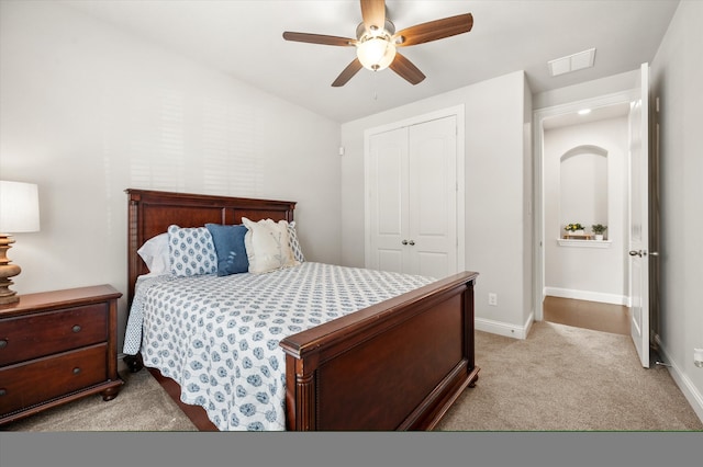 bedroom featuring light colored carpet, a closet, and ceiling fan