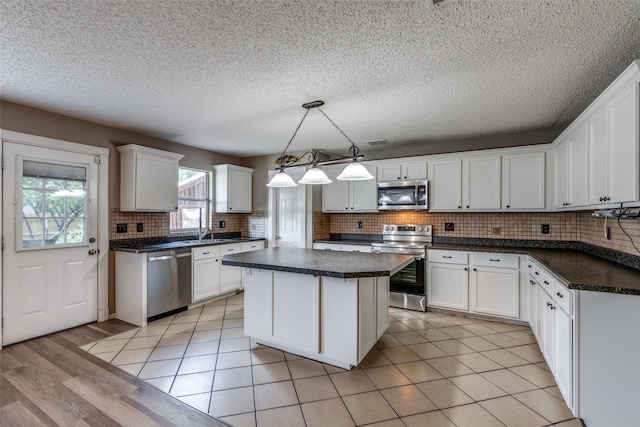 kitchen with decorative backsplash, a center island, white cabinetry, and appliances with stainless steel finishes