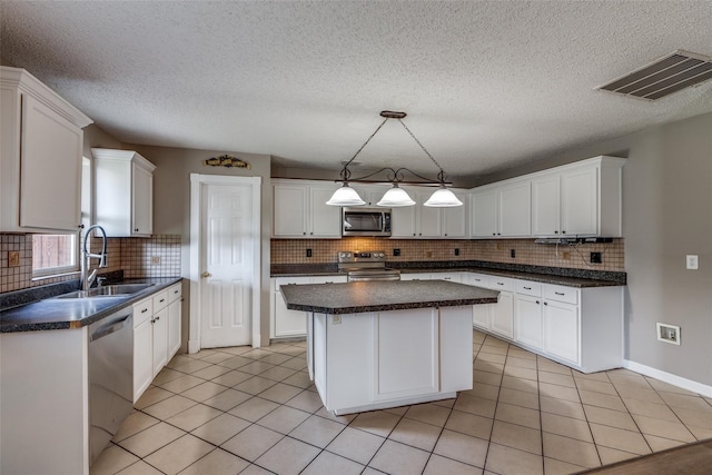 kitchen with white cabinetry, sink, light tile patterned floors, a kitchen island, and appliances with stainless steel finishes