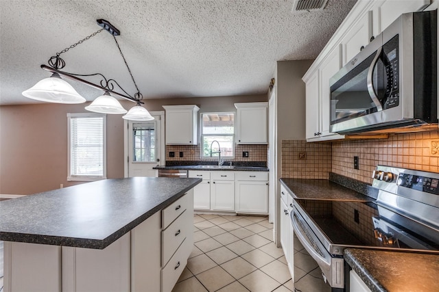 kitchen featuring white cabinets, a center island, backsplash, and appliances with stainless steel finishes