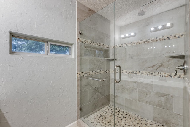 bathroom featuring a shower with shower door and a textured ceiling