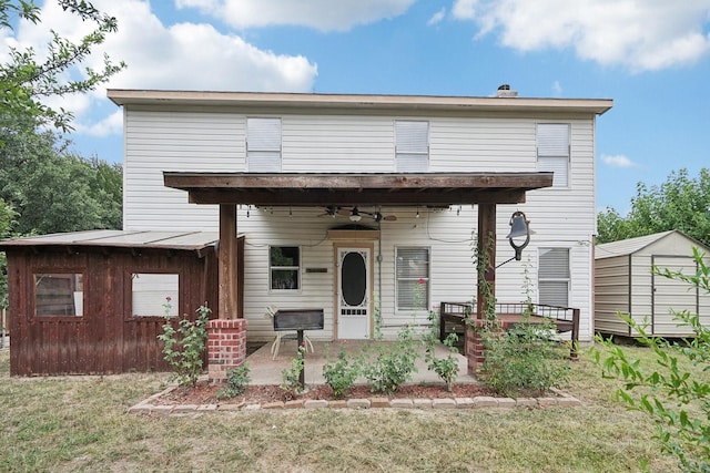 view of front of home featuring ceiling fan, a shed, and a front yard