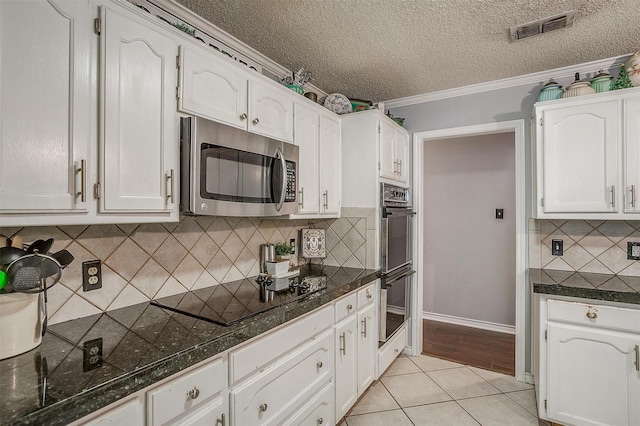 kitchen with white cabinetry, light tile patterned flooring, stainless steel appliances, and ornamental molding