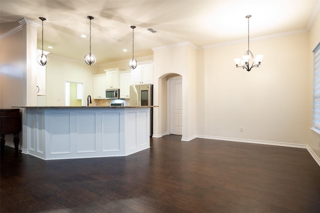 kitchen featuring dark wood-type flooring, stainless steel appliances, white cabinets, decorative light fixtures, and dark stone counters