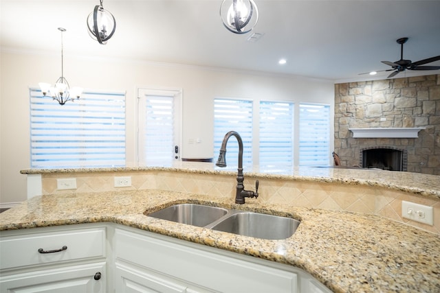 kitchen with ornamental molding, sink, white cabinets, and decorative light fixtures