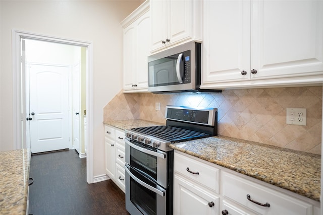 kitchen featuring appliances with stainless steel finishes, light stone countertops, white cabinets, dark hardwood / wood-style flooring, and decorative backsplash