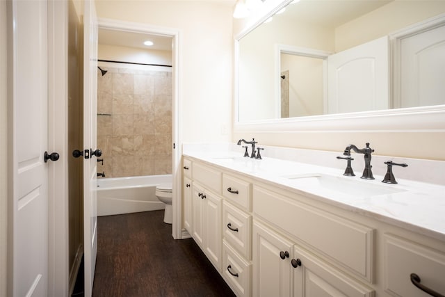 full bathroom featuring tiled shower / bath, vanity, toilet, and hardwood / wood-style floors
