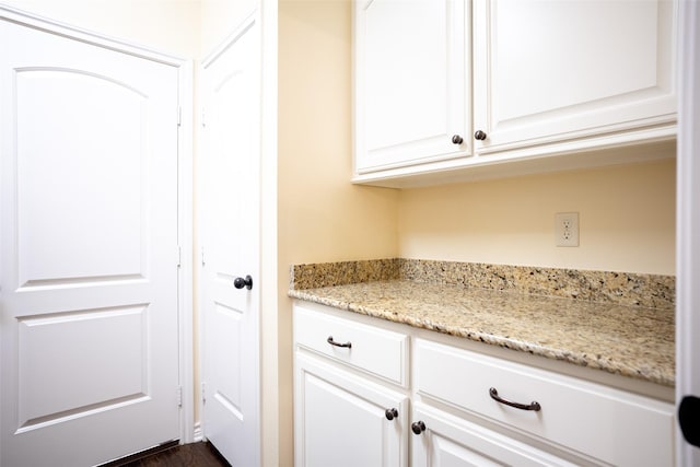 bar with white cabinetry and light stone counters