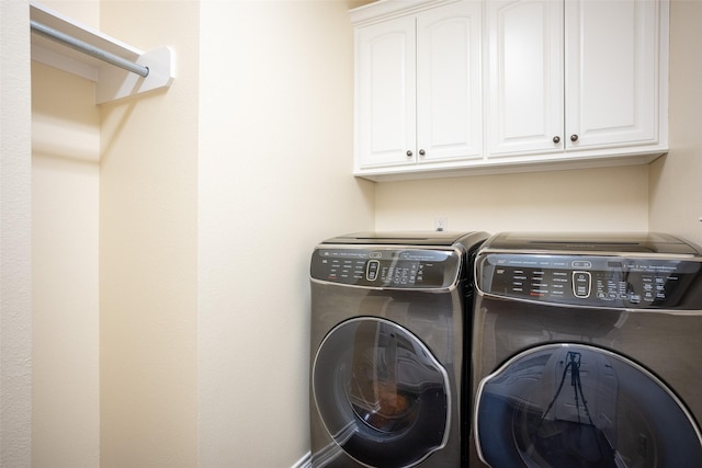 clothes washing area with washing machine and dryer and cabinets