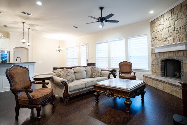 living room featuring ornamental molding, a stone fireplace, dark hardwood / wood-style floors, and ceiling fan