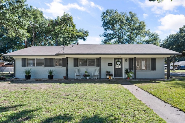 ranch-style home featuring covered porch and a front yard