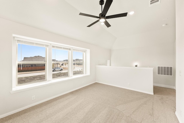 carpeted empty room with ceiling fan, plenty of natural light, and vaulted ceiling