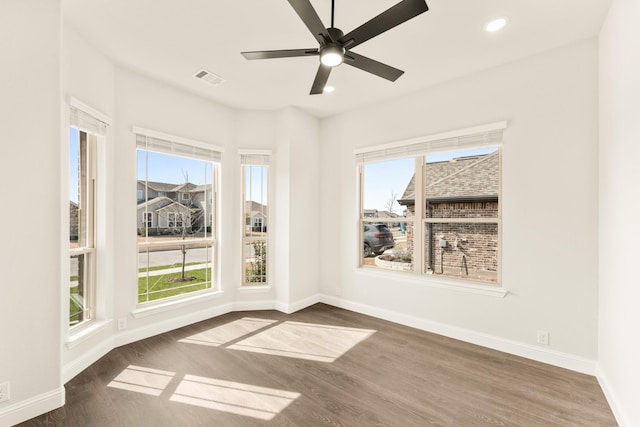 spare room with a wealth of natural light, dark wood-type flooring, and ceiling fan