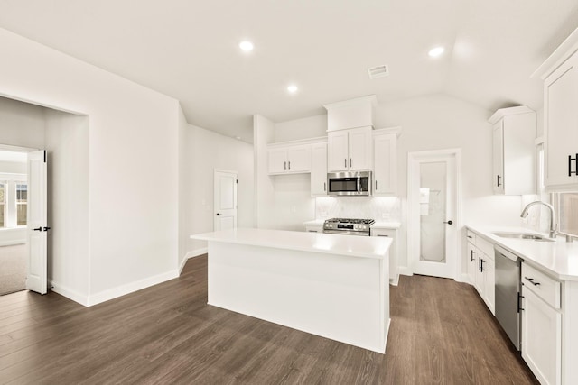 kitchen featuring appliances with stainless steel finishes, white cabinetry, sink, dark hardwood / wood-style flooring, and a center island