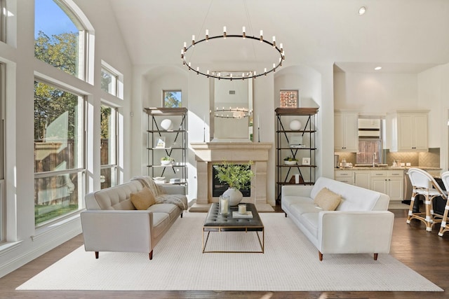 living room featuring a chandelier, hardwood / wood-style flooring, high vaulted ceiling, and sink