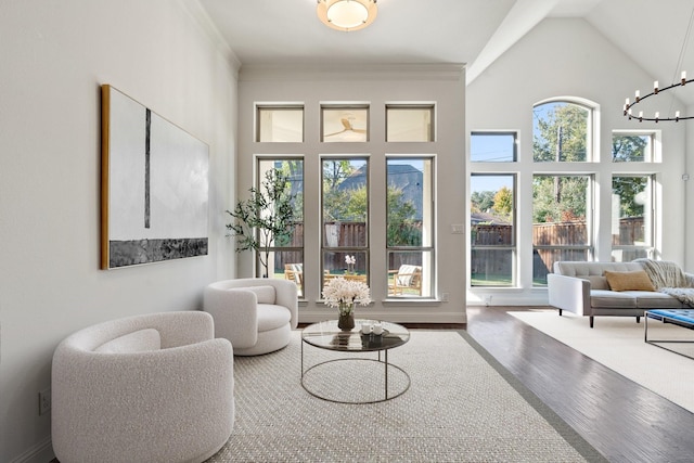 sitting room featuring hardwood / wood-style floors, high vaulted ceiling, ornamental molding, and a notable chandelier