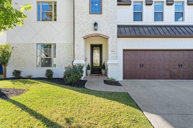 view of exterior entry with driveway, a standing seam roof, a garage, a lawn, and metal roof