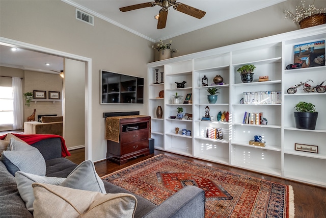 living room with a fireplace, crown molding, ceiling fan, and dark wood-type flooring