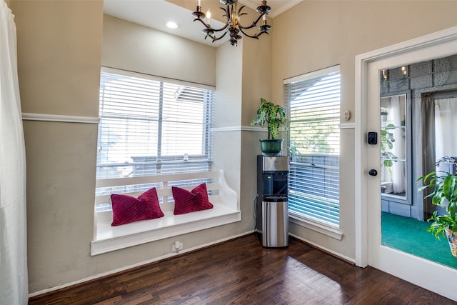 doorway with ornamental molding, dark hardwood / wood-style flooring, an inviting chandelier, and a healthy amount of sunlight