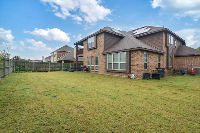 rear view of property featuring a lawn and central AC