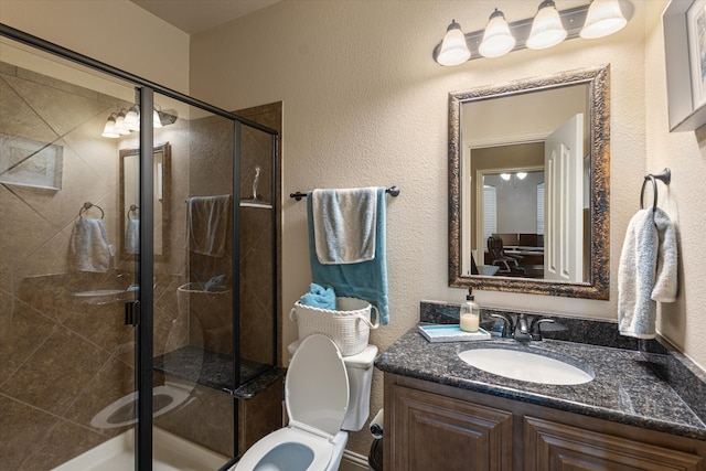 bathroom featuring a shower with door, vanity, and toilet