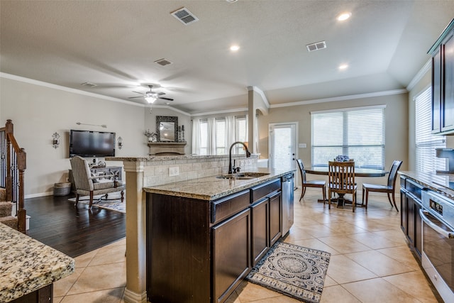 kitchen with light hardwood / wood-style flooring, a kitchen island with sink, crown molding, and sink