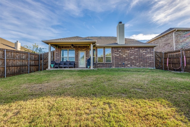 back of house featuring an outdoor living space, ceiling fan, and a lawn