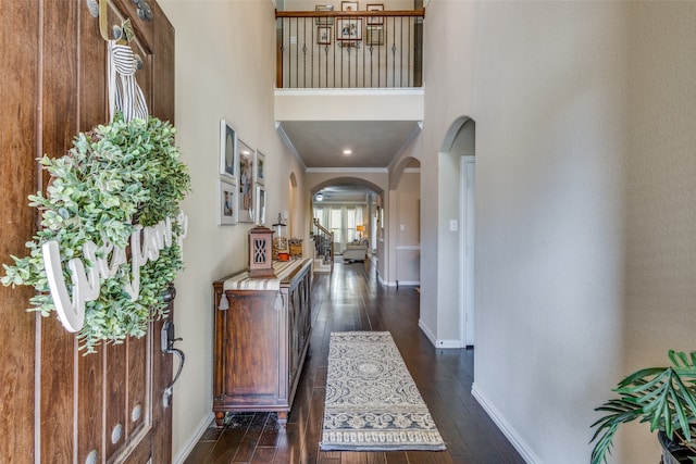 foyer with crown molding, a towering ceiling, and dark wood-type flooring