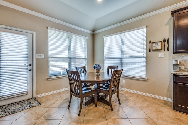 dining area with crown molding, light tile patterned floors, and lofted ceiling