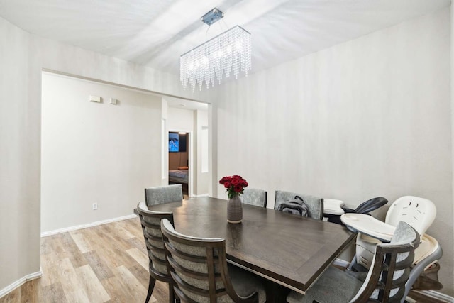 dining room with light hardwood / wood-style flooring and an inviting chandelier