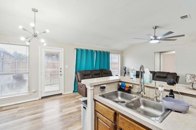 kitchen with light wood-type flooring, plenty of natural light, lofted ceiling, and sink