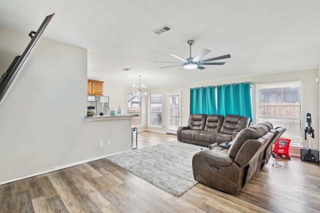 living room with ceiling fan with notable chandelier and light wood-type flooring