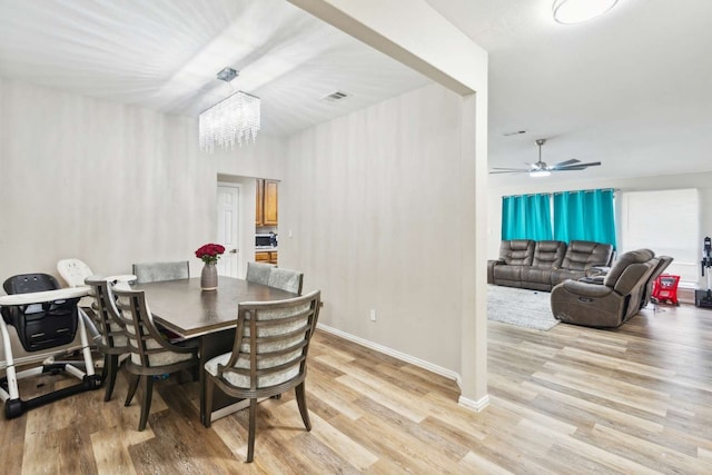 dining room featuring ceiling fan with notable chandelier and light wood-type flooring