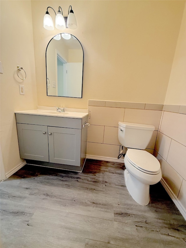 bathroom featuring toilet, vanity, tile walls, and hardwood / wood-style flooring