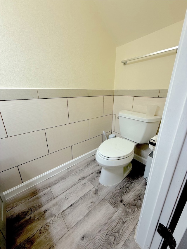 bathroom with hardwood / wood-style flooring, toilet, and tile walls