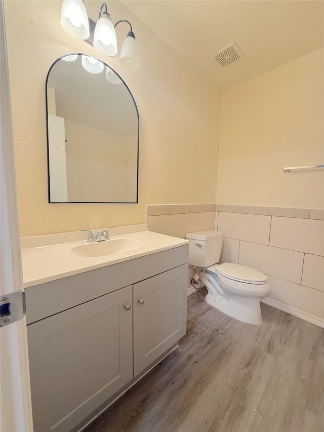 bathroom featuring hardwood / wood-style flooring, vanity, toilet, and tile walls