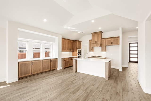 kitchen with lofted ceiling, light wood-style floors, built in microwave, and brown cabinetry