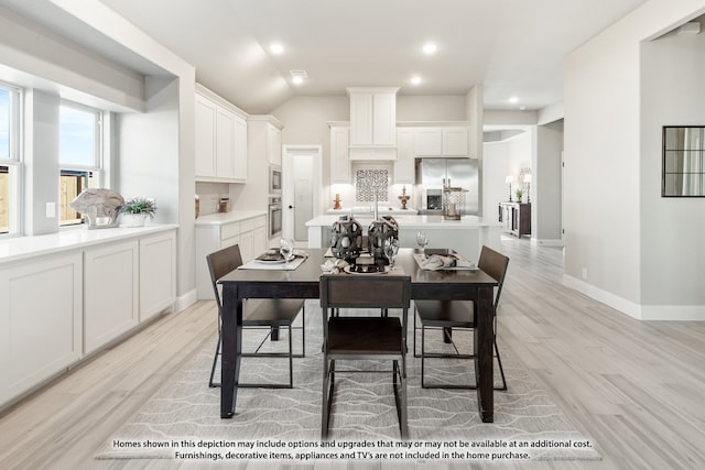 dining room featuring light hardwood / wood-style flooring, lofted ceiling, and sink