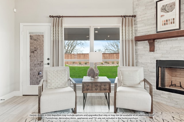 living area with a stone fireplace and hardwood / wood-style flooring