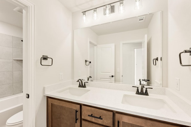 bathroom with visible vents, a sink, toilet, and double vanity