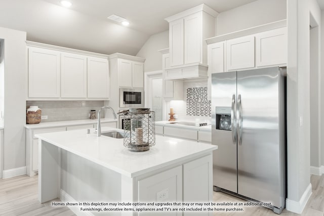 kitchen featuring lofted ceiling, sink, tasteful backsplash, white cabinetry, and stainless steel appliances